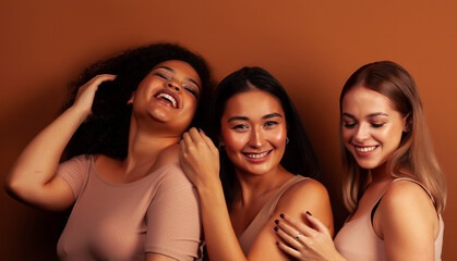 young pretty asian, caucasian, african woman posing cheerful together on brown background,...