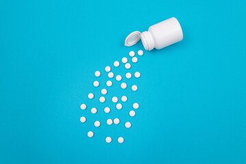 Global Pharmaceutical Industry and Medicinal Products - White Pills or Tablets Scattered from the Bottle, Lying on Blue Background, Top View, Flat Lay