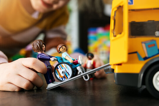 kid playing with Playmobil toys on the floor. school bus transportation for person in wheelchair. disability acceptance concept
