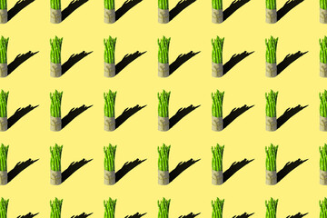 Bunches of fresh asparagus on a green background. Seamless repeating pattern.