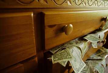 US money spilling out dresser drawer.