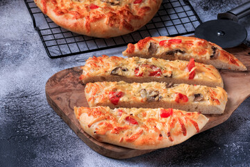 Pizza flatbread on a thick dough base with cheese, tomato and other ingredients top view. 