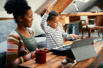 Small black girl plays synthesizer while spending time with her mother at home.