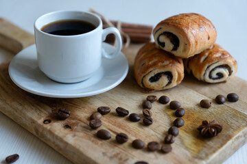 Coffee grinder, heart shaped coffee beans and cinnamon on a wooden surface. a cup of aromatic coffee and fresh buns for the new year 2022.