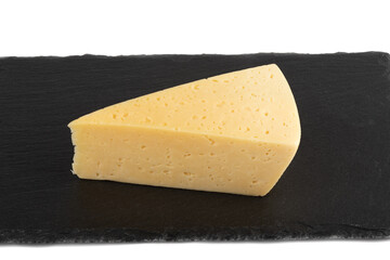 A piece of hard cheese on a stone cutting board.