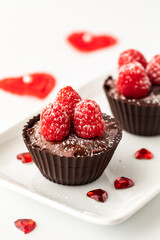 Vertical view of chocolate raspberry cups surrounded by Valentine decorations.