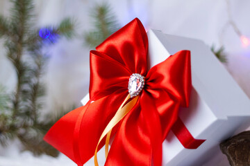 A Christmas gift decorated with a beautiful bow on a light background with a fir twig. Gifts, joy, surprise. Selective focus. the concept of Christmas and New Year.