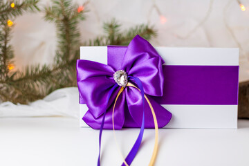A Christmas gift decorated with a beautiful bow on a light background with a fir twig. Gifts, joy, surprise. Selective focus. the concept of Christmas and New Year.