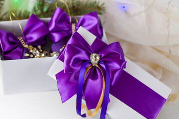 A Christmas gift decorated with a beautiful bow on a light background with a fir twig. Gifts, joy, surprise. Selective focus. the concept of Christmas and New Year.