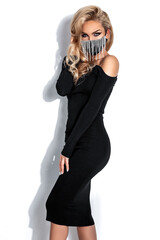 Elegant fashion. Stunning blonde woman in elegant black dress and mask isolated on white...