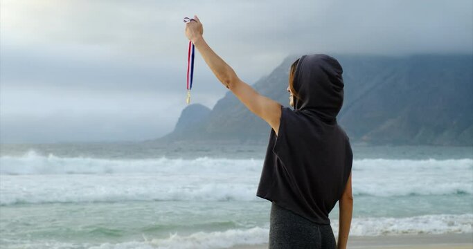 athletic slim girl holding gold medal in her hands after swimming competition. Sport winner gold medal first place in competitions. Award of Victory. Olympic gold medal. sportive woman on ocean beach