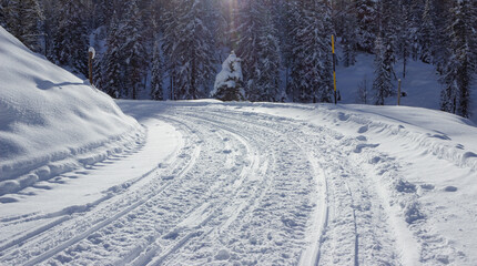 Beautiful mountain road covered with snow in the middle of the forest.