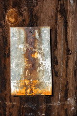 Rusty metal plate on a wooden brown old surface