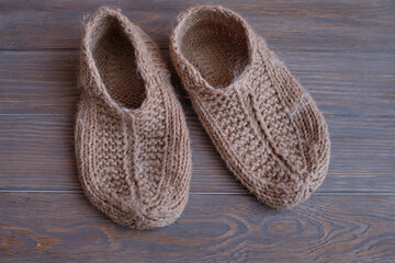 Wool slippers. Rustic Knitted slippers on wood floor. handmade knitted warm slippers on a wooden background. close-up, top view..