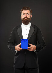 mature man in tux holding gift box, purchase
