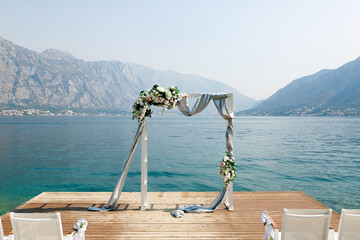 Wedding arch stands on a wooden pier overlooking the mountains