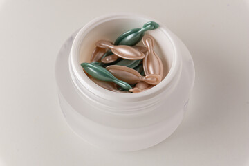Night and day face capsules in a white jar on a white background. Facial serum cosmetic capsules.