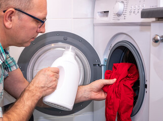 Mudchina, a Caucasian, middle-aged, puts colored clothes in the washing machine.