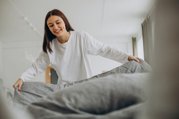 Woman making her bed after sleep in the morning