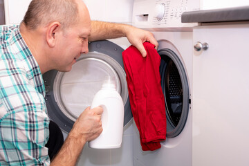 Mudchina, a Caucasian, middle-aged, puts colored clothes in the washing machine.