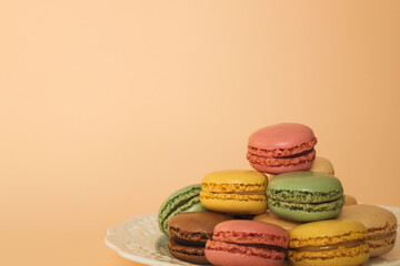 French macaroons on an apricot background. Delicious colorful almond cookies, dessert. Place for text