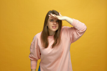 Attentive concentrated young girl staring looking at camera with hand near forehead, seek...