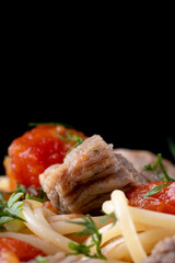 pasta with tomato sauce and meat on white plate and black background. Selective focus.