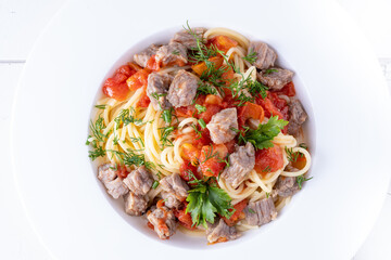 Pasta in tomato sauce and meat on white plate and white background.