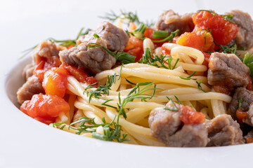Pasta in tomato sauce and meat on white plate and white background.