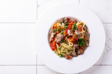 pasta with tomato sauce and meat on white plate and white ceramic bacground. Top view.