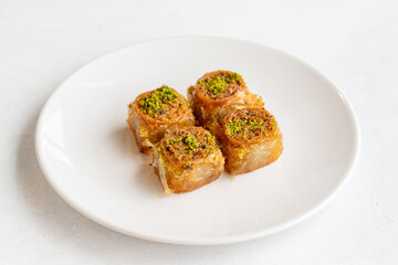 Pistachio baklava dessert on a white background. Turkish sweet dessert concept. plate of pistachio baklava. sherbet sweet Mediterranean bakery. close up. selective focus.