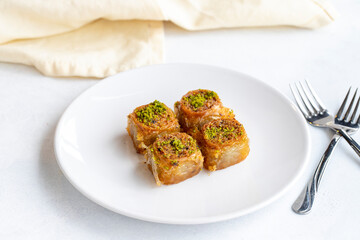 Pistachio baklava dessert on a white background. Turkish sweet dessert concept. plate of pistachio baklava. sherbet sweet Mediterranean bakery. close up. selective focus.