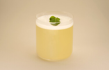 Cocktail in a glass glass with foam and mint.