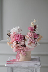 A luxurious bouquet of flowers in a hat box. Composition with pink and white flowers and eucalyptus in a round box. Modern Floristry.