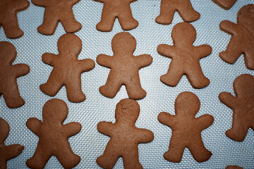 gingerbread men, cooked at home, lie on a white silicone mat after baking. healthy food without...