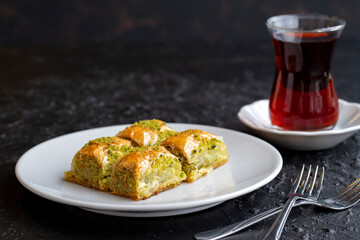 Pistachio baklava dessert on a dark background. Turkish sweet dessert concept. plate of pistachio baklava. sherbet sweet Mediterranean bakery. close up. selective focus.