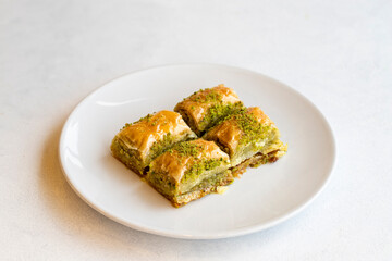 Pistachio baklava dessert on a white background. Turkish sweet dessert concept. plate of pistachio baklava. sherbet sweet Mediterranean bakery. close up. selective focus