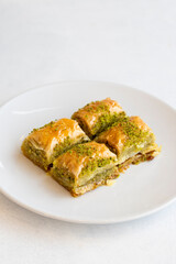 Pistachio baklava dessert on a white background. Turkish sweet dessert concept. plate of pistachio baklava. sherbet sweet Mediterranean bakery. close up. selective focus