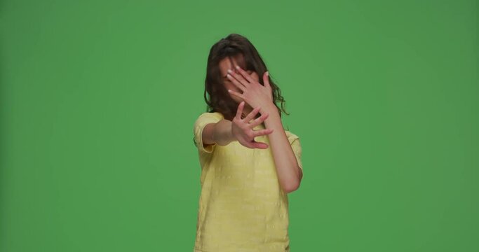 Young girl covering eyes with hands doing stop gesture with fear expression, feel disgust on chromakey green background