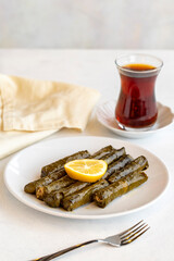 Delicious dolma (sarma) stuffed grape leaves rice, white yogurt sauce. Stuffed grape leaves on white background. Lebanese dolma sarma on plate. Lebanon turkish greek middle eastern cuisine.