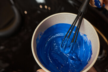 girl in white rubber protective gloves holding a brush in her hands and stirring hair dye close-up...