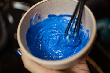 girl in white rubber protective gloves holding a brush in her hands and stirring hair dye close-up...