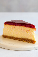 Cheesecake on white background. Greek sweet dessert concept. plate of sliced cheesecake. Cheesecake with raspberry gel filling. Mediterranean bakery. close up. selective focus. Vertical view.