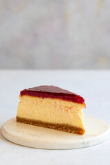 Cheesecake on white background. Greek sweet dessert concept. plate of sliced cheesecake. Cheesecake with raspberry gel filling. Mediterranean bakery. close up. selective focus. Vertical view.
