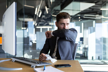 Sick man working in the office, businessman has a bad cough, working in a modern office at the...