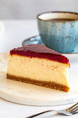 Cheesecake on white background. Greek sweet dessert concept. plate of sliced cheesecake. Cheesecake with raspberry gel filling. Mediterranean bakery. close up. selective focus. Vertical view.