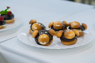 Assortment of delicious fresh shortcrust tart cakes with chocolate and sweet mushrooms on white plate for sale at restaurant, cafe. Dessert, culinary and confectionery concept