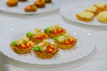 Assortment of delicious fresh shortcrust tart cakes with cream and sweet mushrooms on white plate for sale at restaurant, cafe. Dessert, culinary and confectionery concept