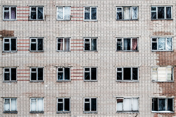 Abandoned building Soviet epoch, wall with dark windows. Large brick wall, gray pattern background...