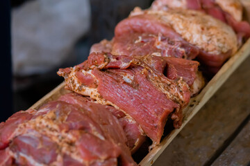 Close up: freshly juicy marinated meat with spices and onion on wooden board at summer local food market. Outdoor cooking, gastronomy, cookery, street food concept